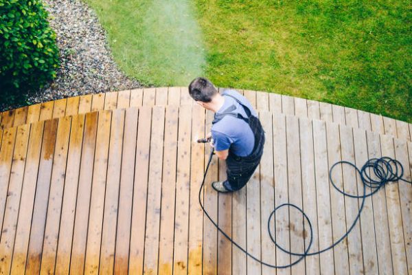 cleaning terrace with a power washer - high water pressure cleaner on wooden terrace surface